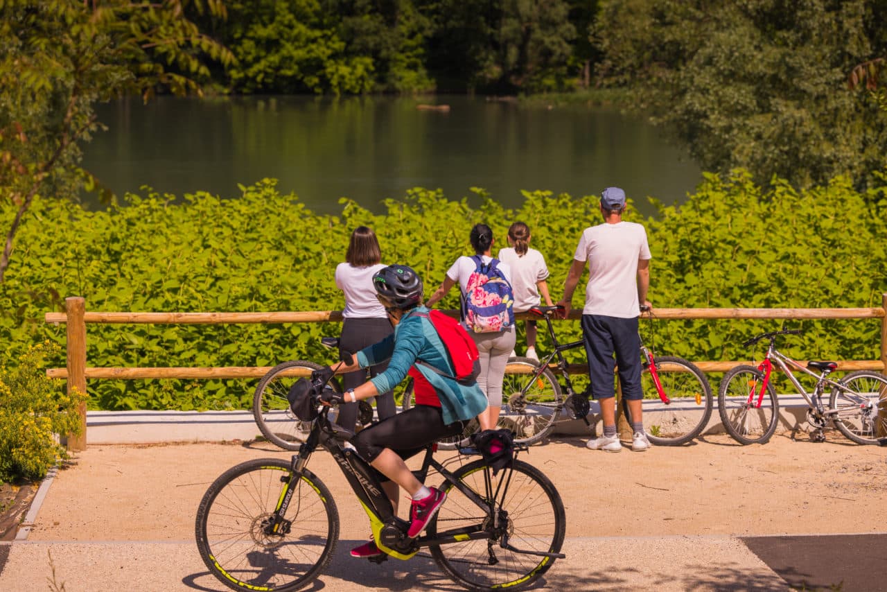 Sur la ViaRhôna un cycliste à vélo en Sud Ardèche regardant des promeneurs qui admirent le Rhône.
